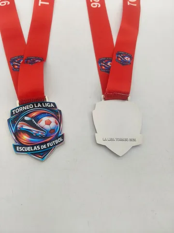 Torneo La Liga · Escuelas de Fútbol. Full color con forma de escudo y cinta roja impresa.